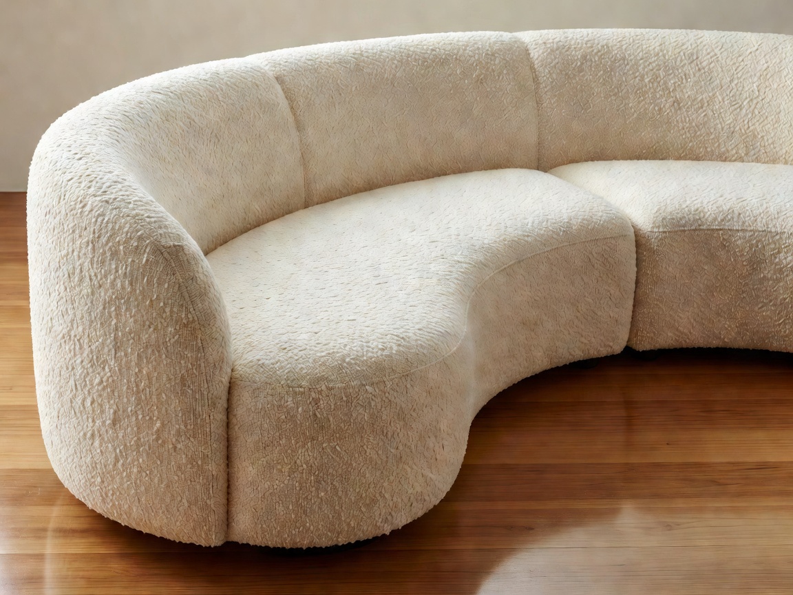 Sculptural curved modular sofa upholstered in white wool bouclé positioned in a contemporary architectural salon